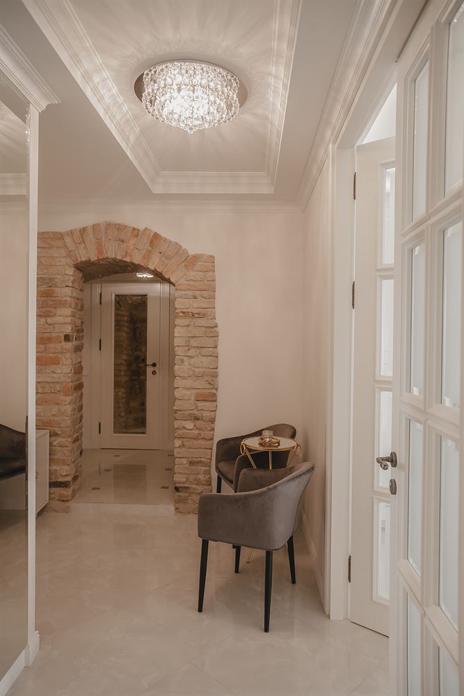 The studio’s hall: a crystal chandelier, an arch of old brick and velvet armchairs