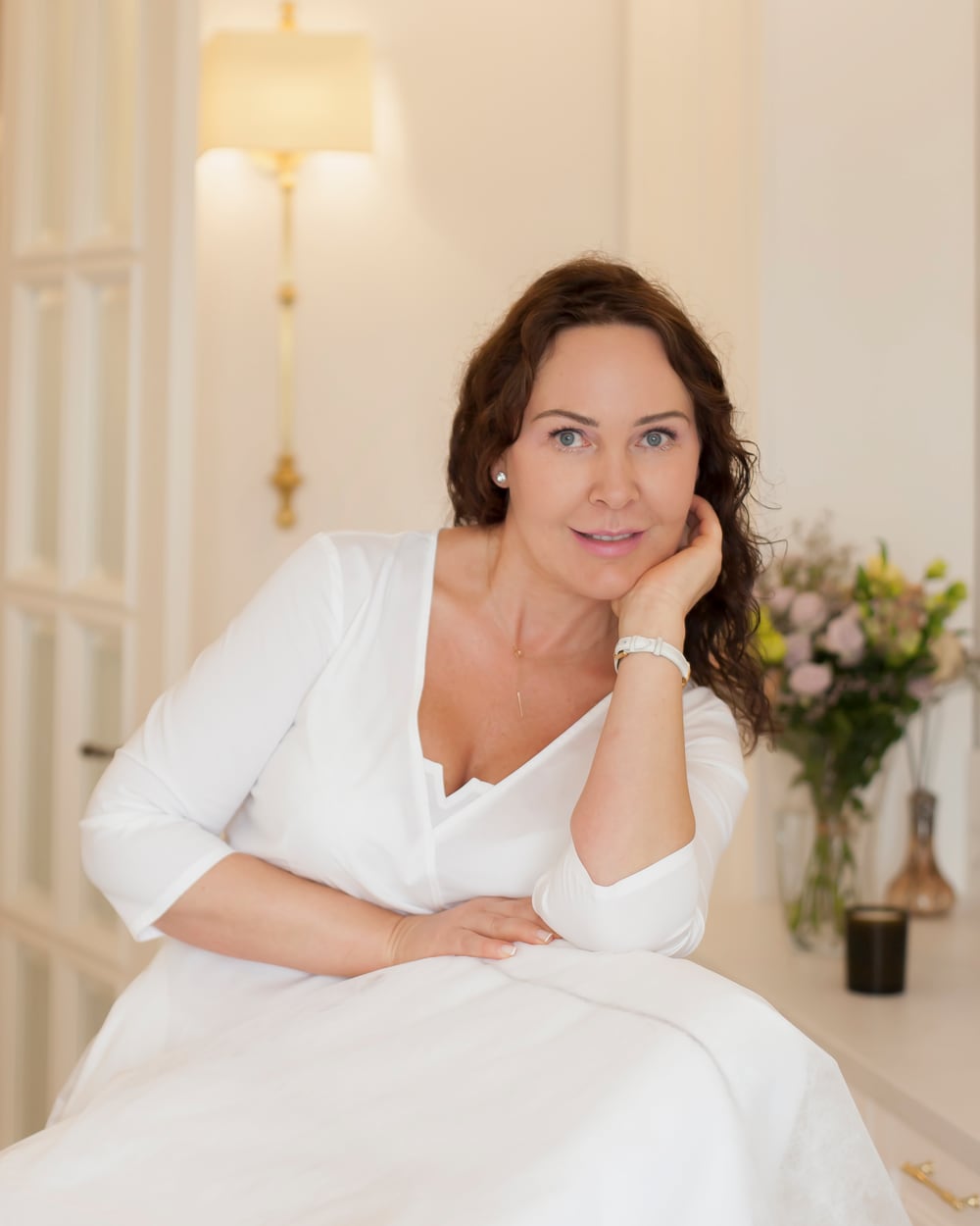 Besišypsanti Žana Mitiajeva šviesiame studijos kabinete, skruostą atrėmusi į delną