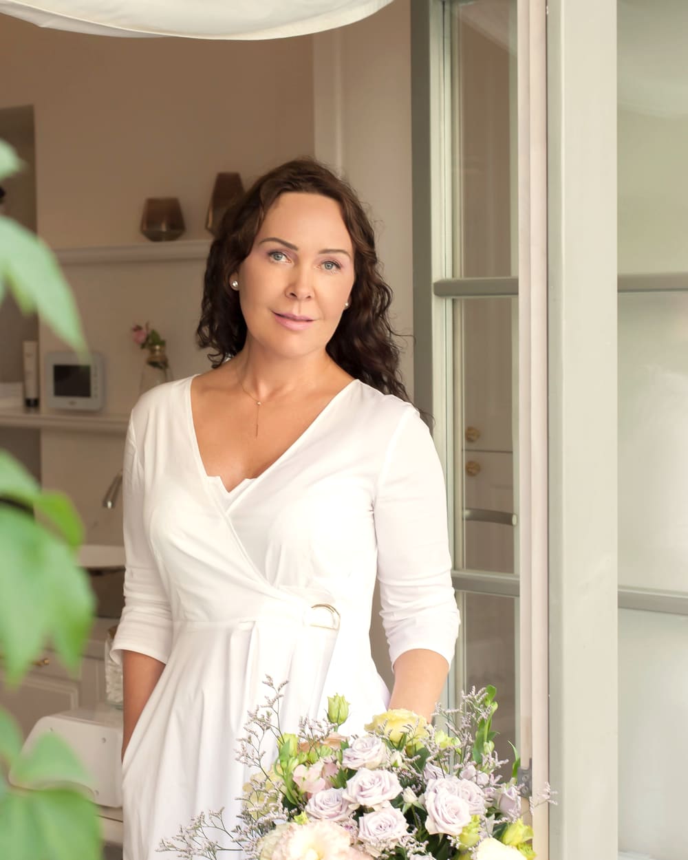 Cosmetologist Žana Mitiajeva with a bouquet of flowers by the studio window